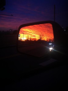 sunset in seen in a car's mirror